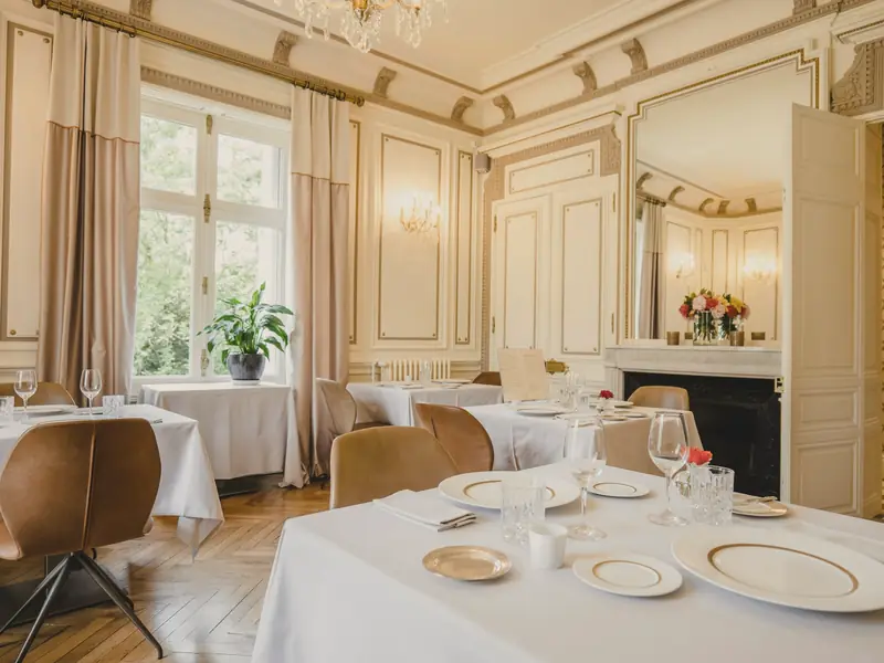 A restaurant dining room with tables set beside a fireplace